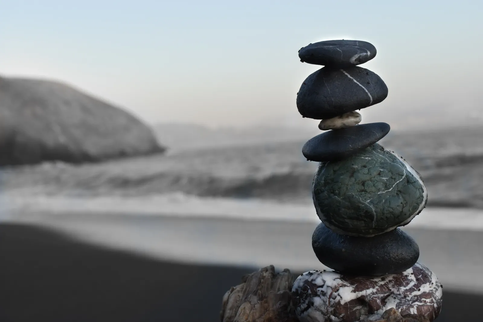 A stack of rocks on top of a piece of wood, balanced