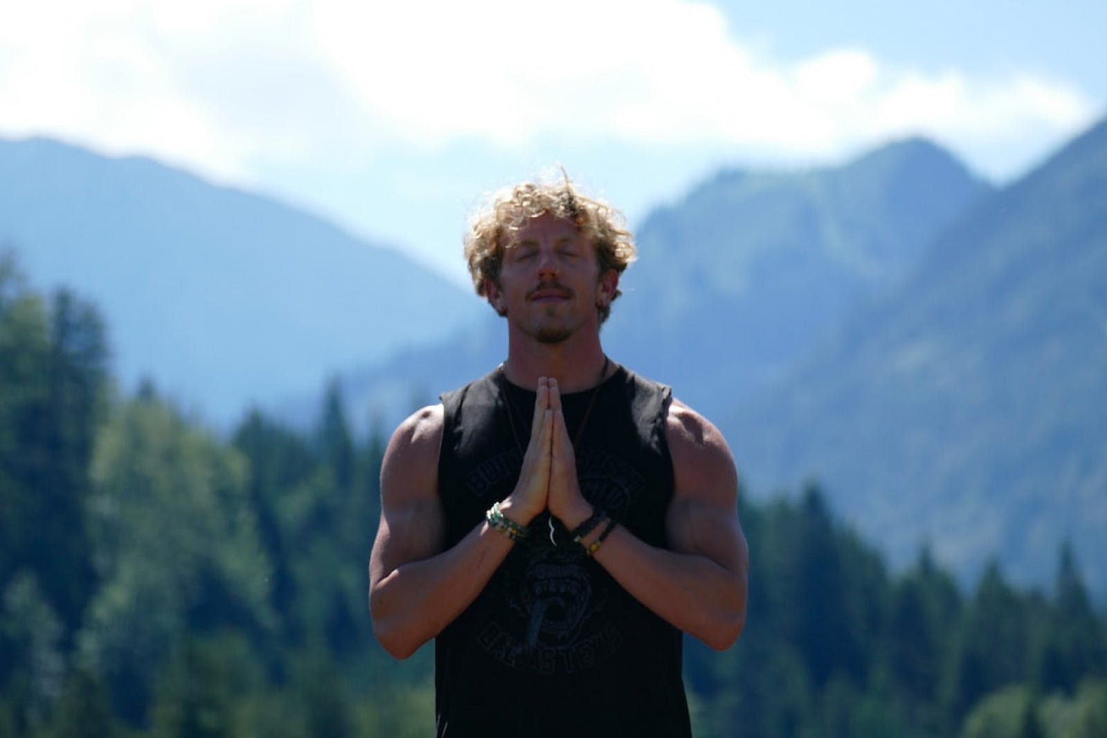 A man meditating in front of mountains.