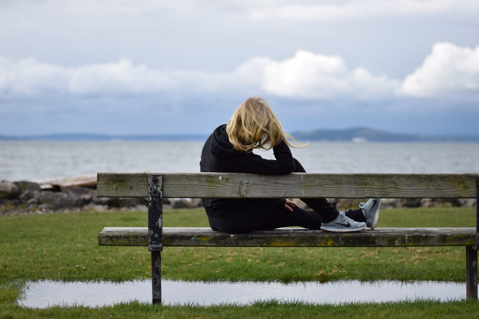 A woman sitting on a bench reflecting