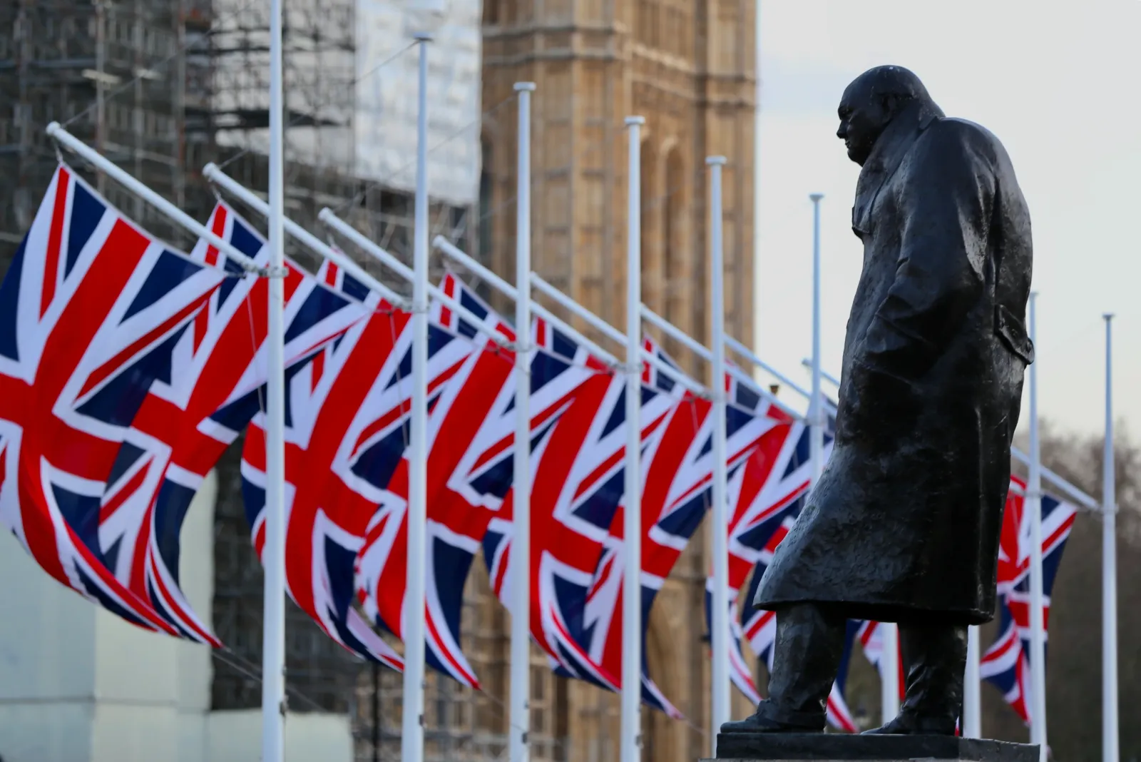 A statue of Winston Churchill in front of British flags.