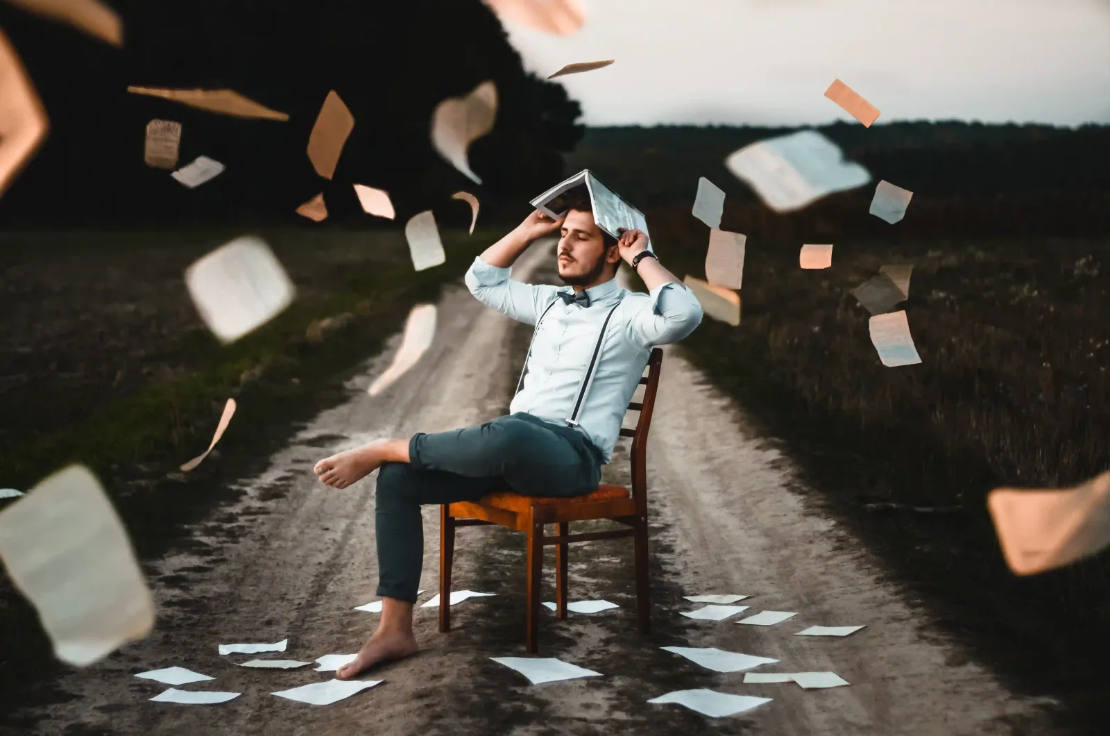 A man sat on a chair with a open book on his head to illustrate visual storytelling