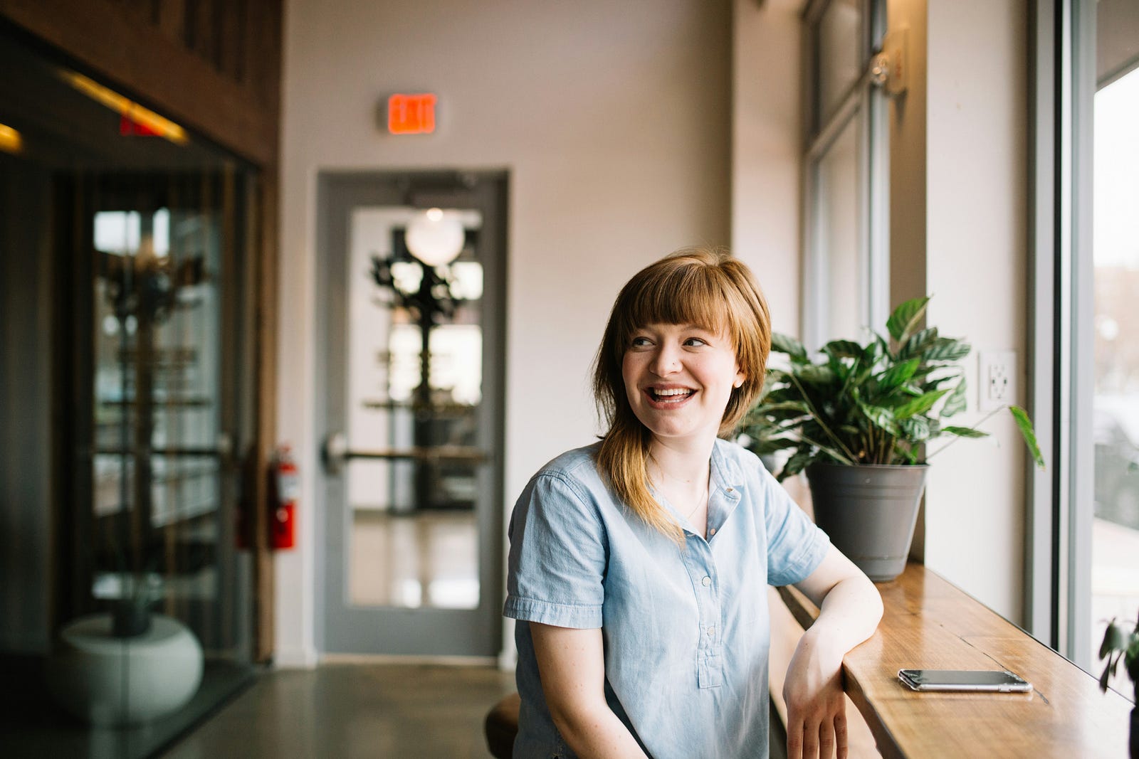 A solopreneur smiling at a window in a coffee shop.