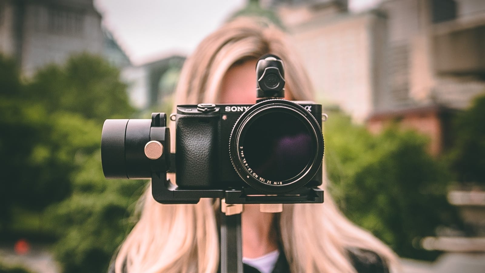 woman holding a camera with lense facing pov